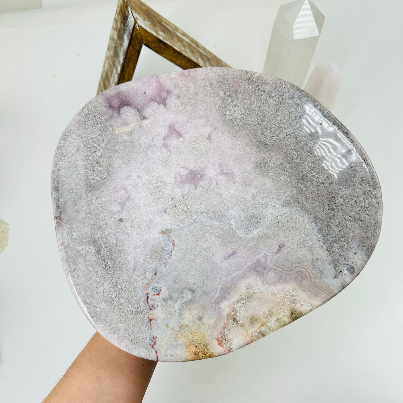 hand holding up pink amethyst plate with decorations in the background