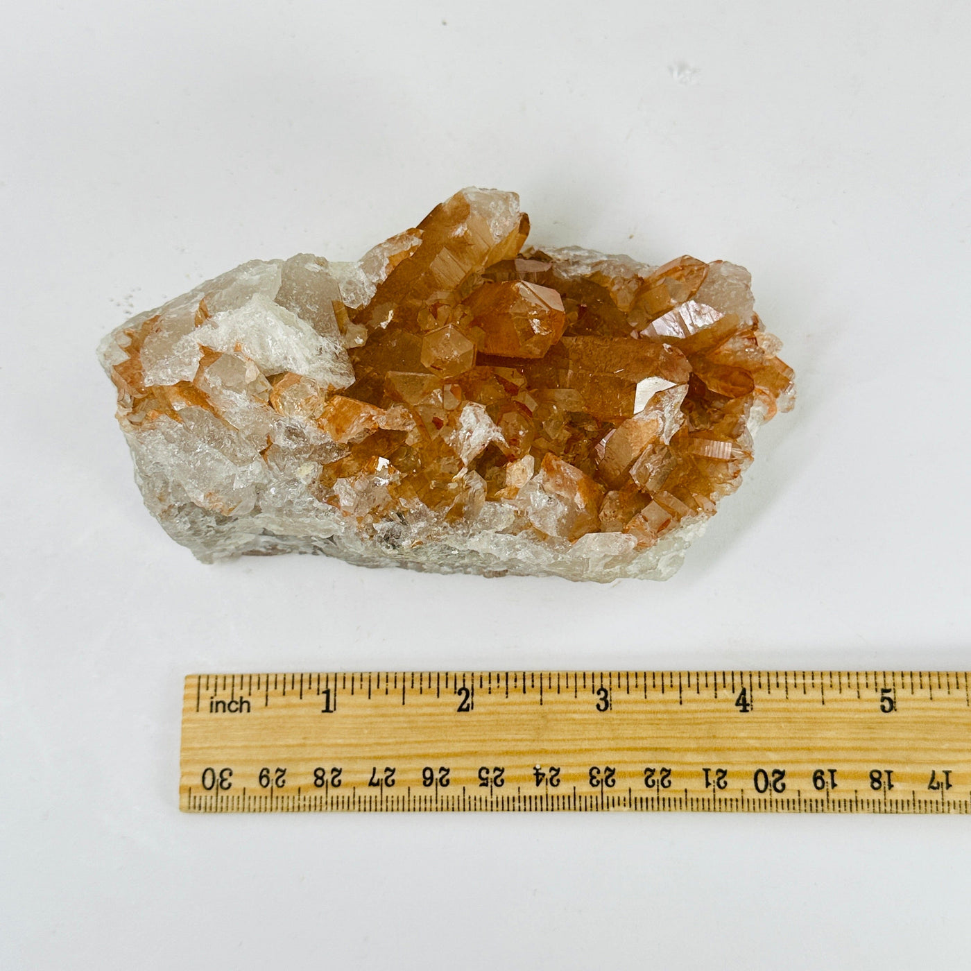 tangerine quartz cluster next to a ruler for size reference