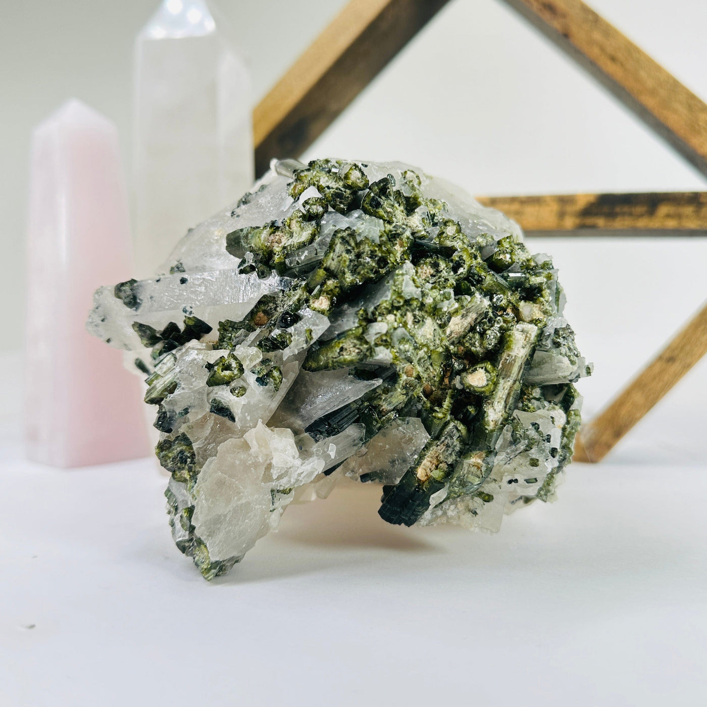 green tourmaline on matrix with decorations in the background