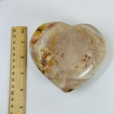 pink amethyst heart next to a ruler for size reference