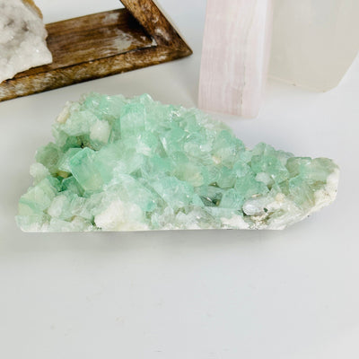 green apophyllite on matrix with decorations in the background