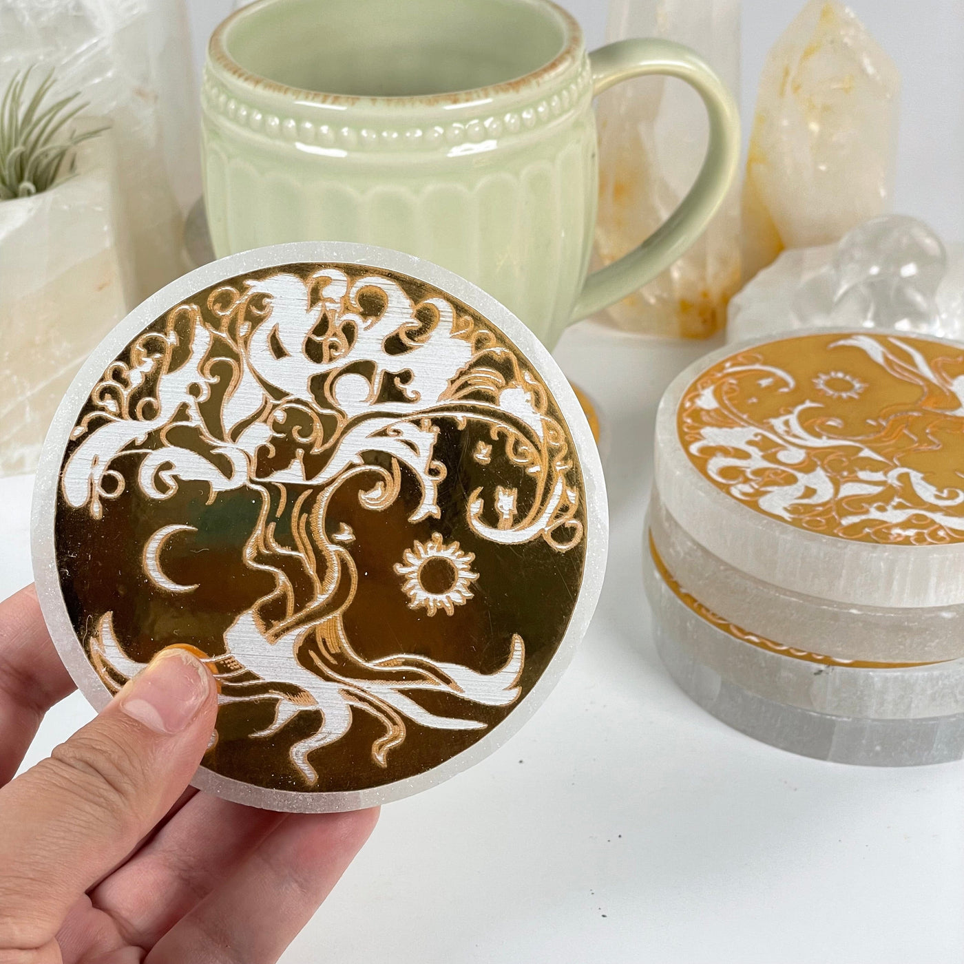 Selenite Crystal Coasters with Gold Foil Tree of Life Decal - You Get All hand holding one for size reference with rest in the background in a stack 