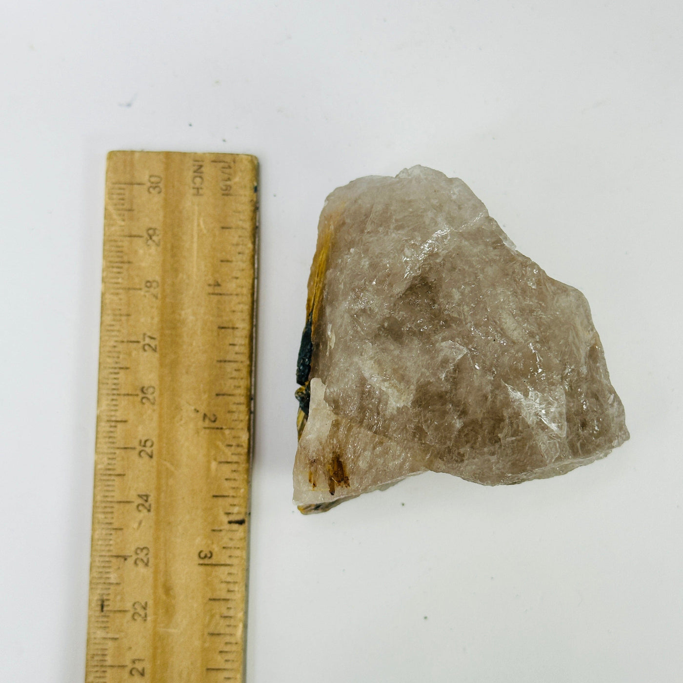 rutilated smokey quartz next to a ruler for size reference
