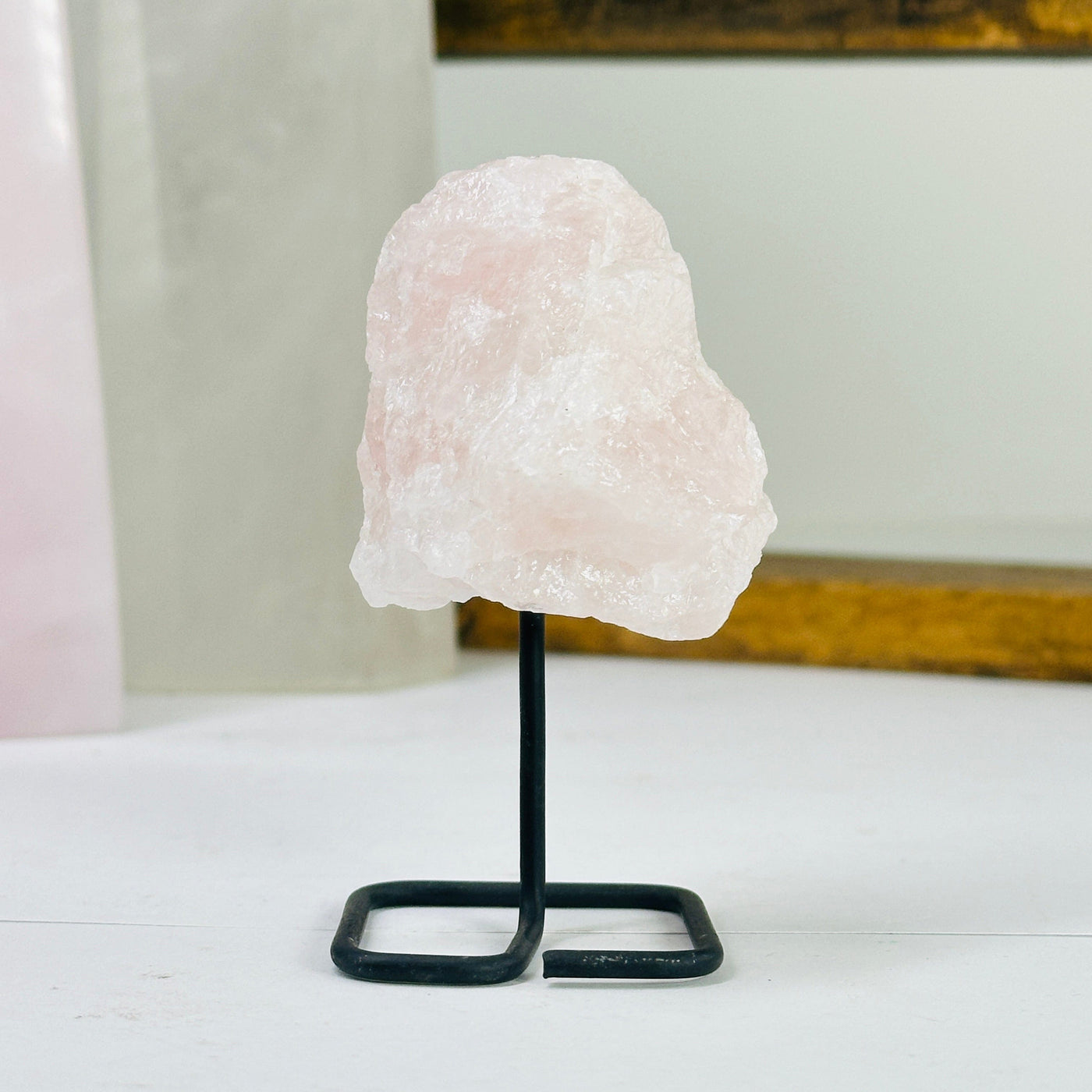 Rose quartz on metal stand with decorations in the background