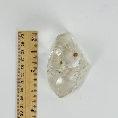 polished crystal quartz with inclusions next to a ruler for size reference