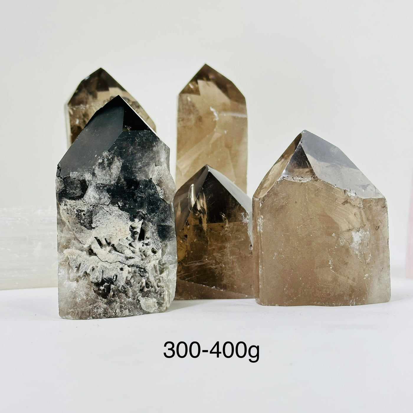 300-400g smoky quartz semi polished point with decorations in the background