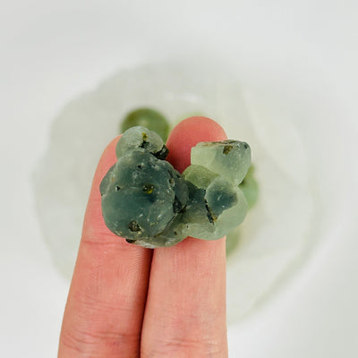 fingers holding up epidote with prehnite cluster
