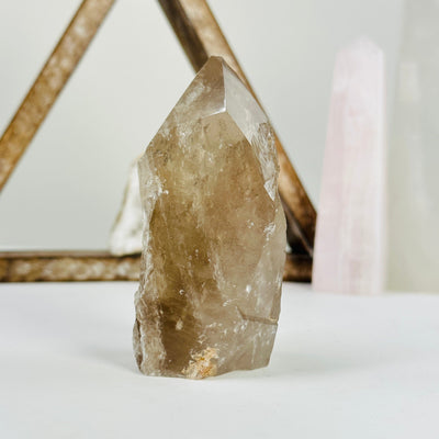 smoky quartz semi polished point with decorations in the background