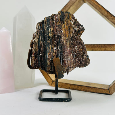 Tourmaline with mica on Metal stand with decorations in the background 