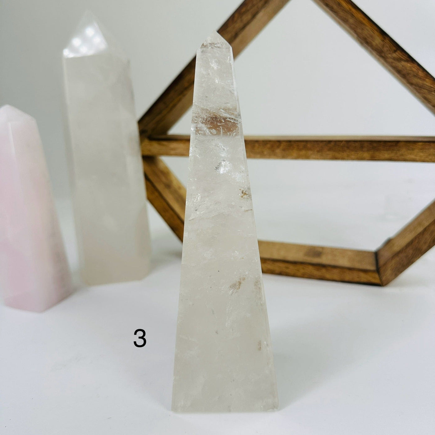 CRYSTAL QUARTZ OBELISK WITH DECORATIONS IN THE BACKGROUND
