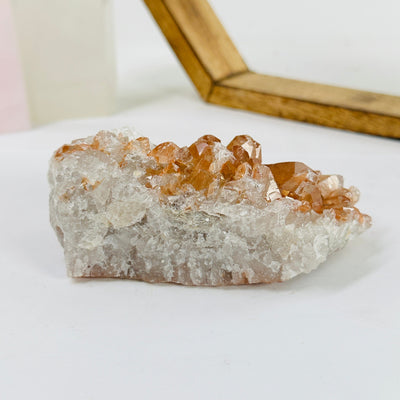 tangerine quartz cluster with decorations in the background