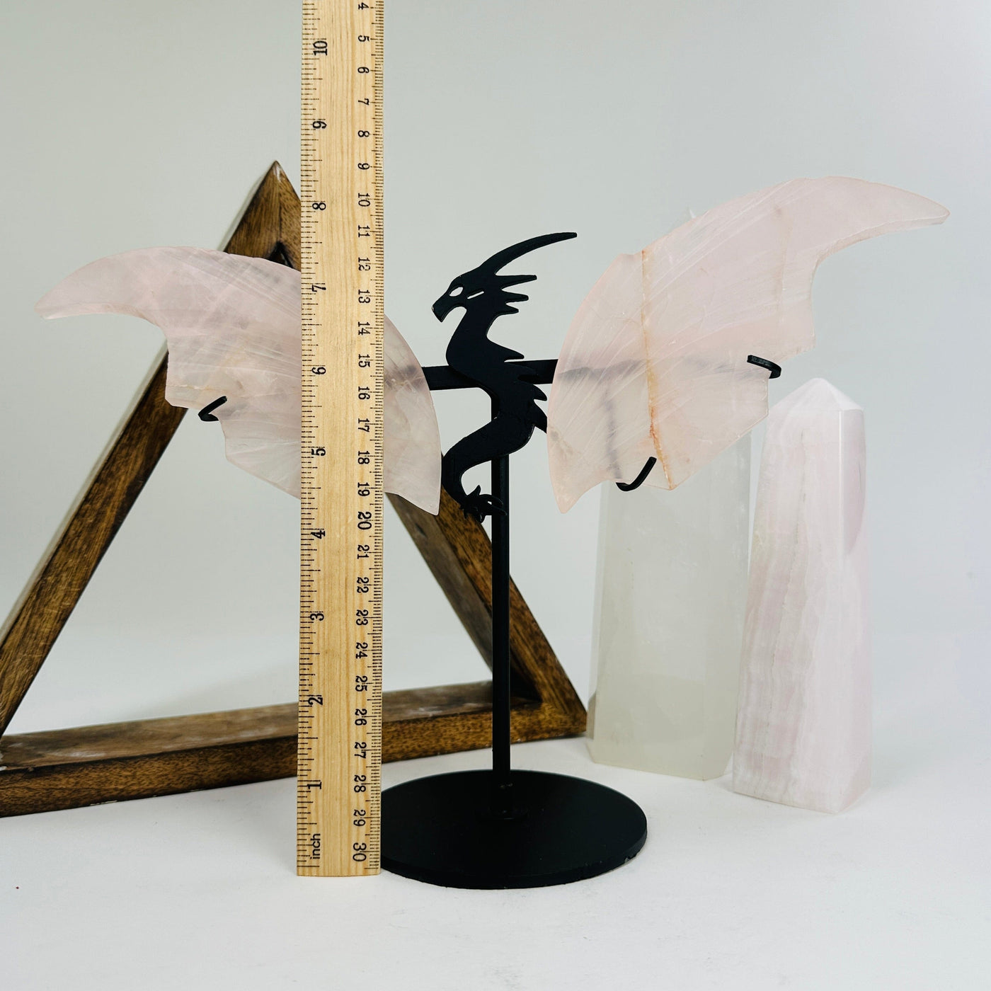 rose quartz dragon on metal stand next to a ruler for size reference