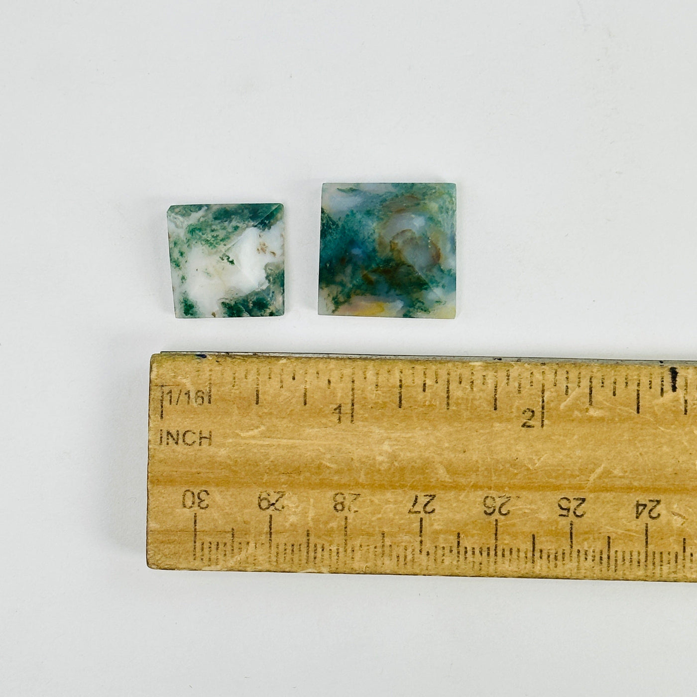 moss agate pyramids next to a ruler for size reference