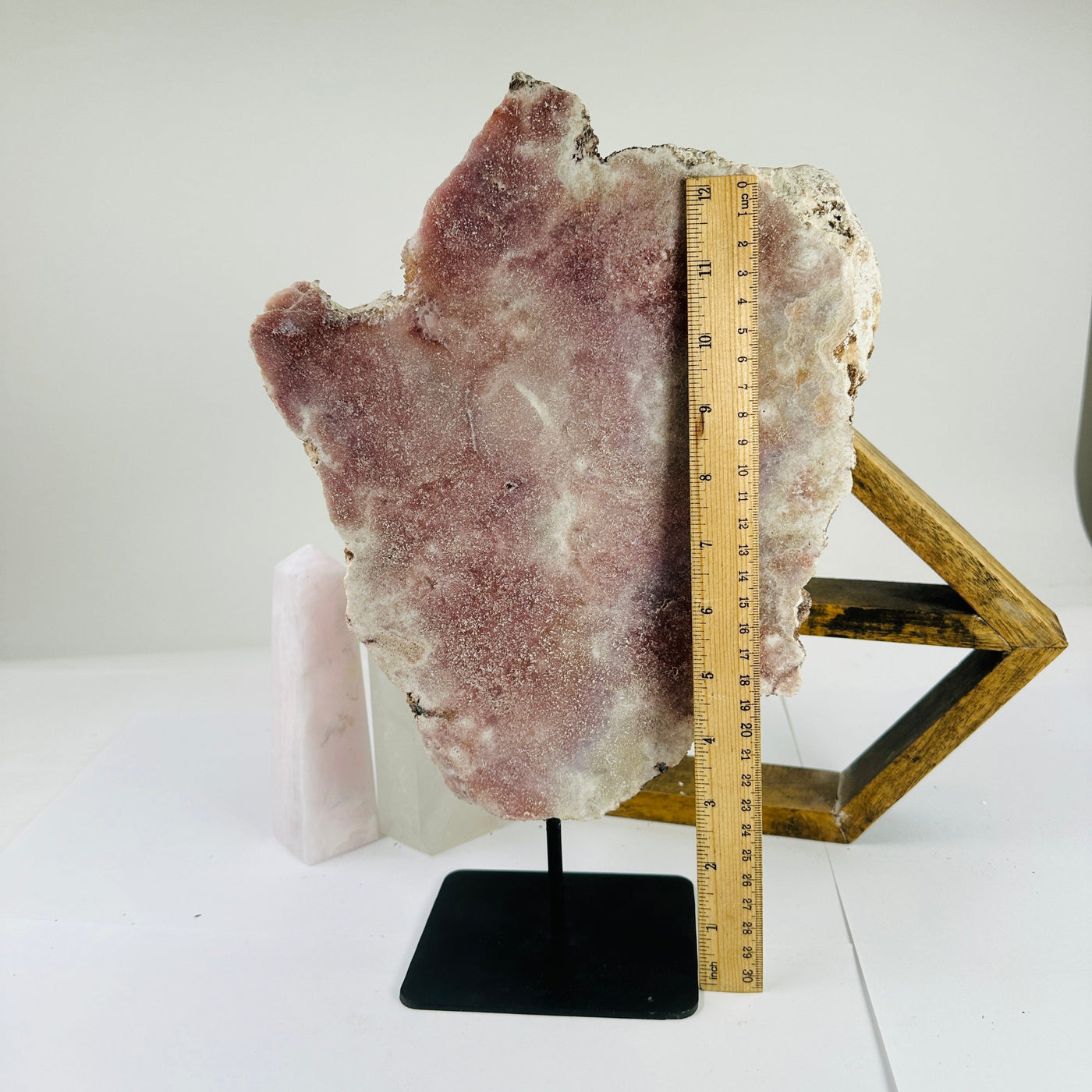 pink amethyst on stand next to a ruler for size reference