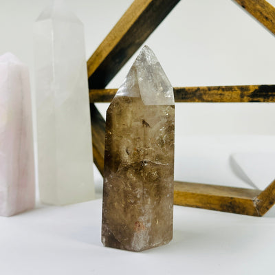 smokey quartz point with decorations in the background