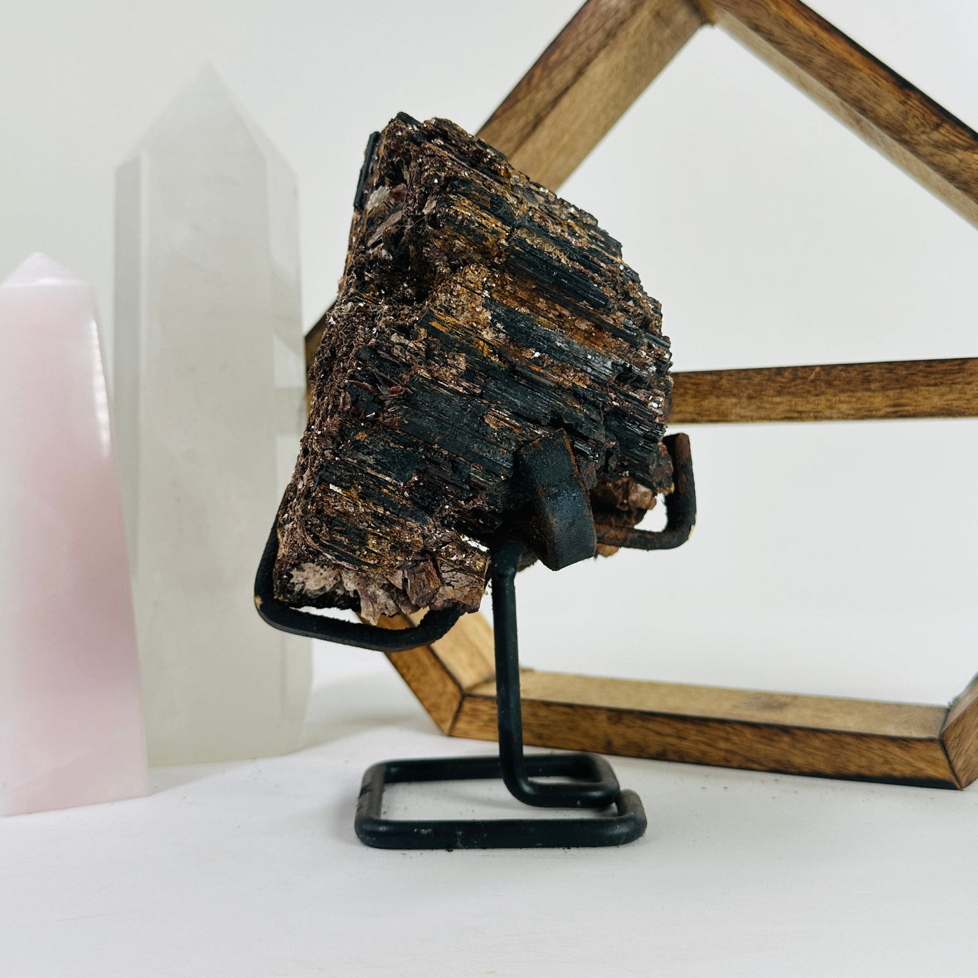 Tourmaline with mica on Metal stand with decorations in the background 