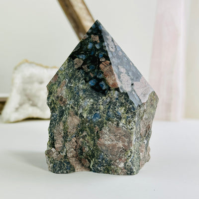 rhyolite semi polished point with decorations in the background