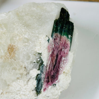 watermelon tourmaline on matrix with decorations in the background