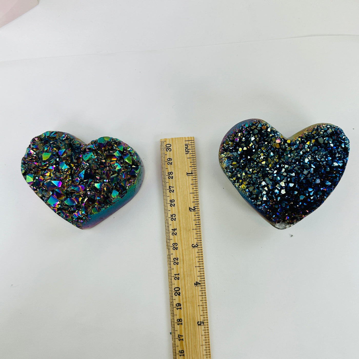 Rainbow titanium heart next to a ruler for size reference 