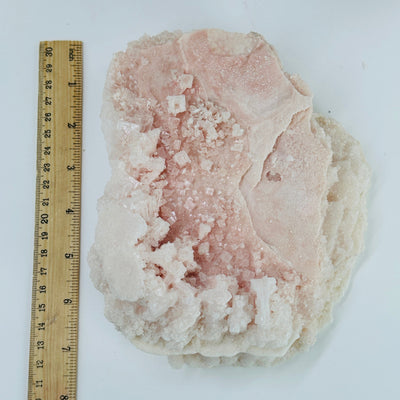 pink halite cluster next to a ruler for size reference