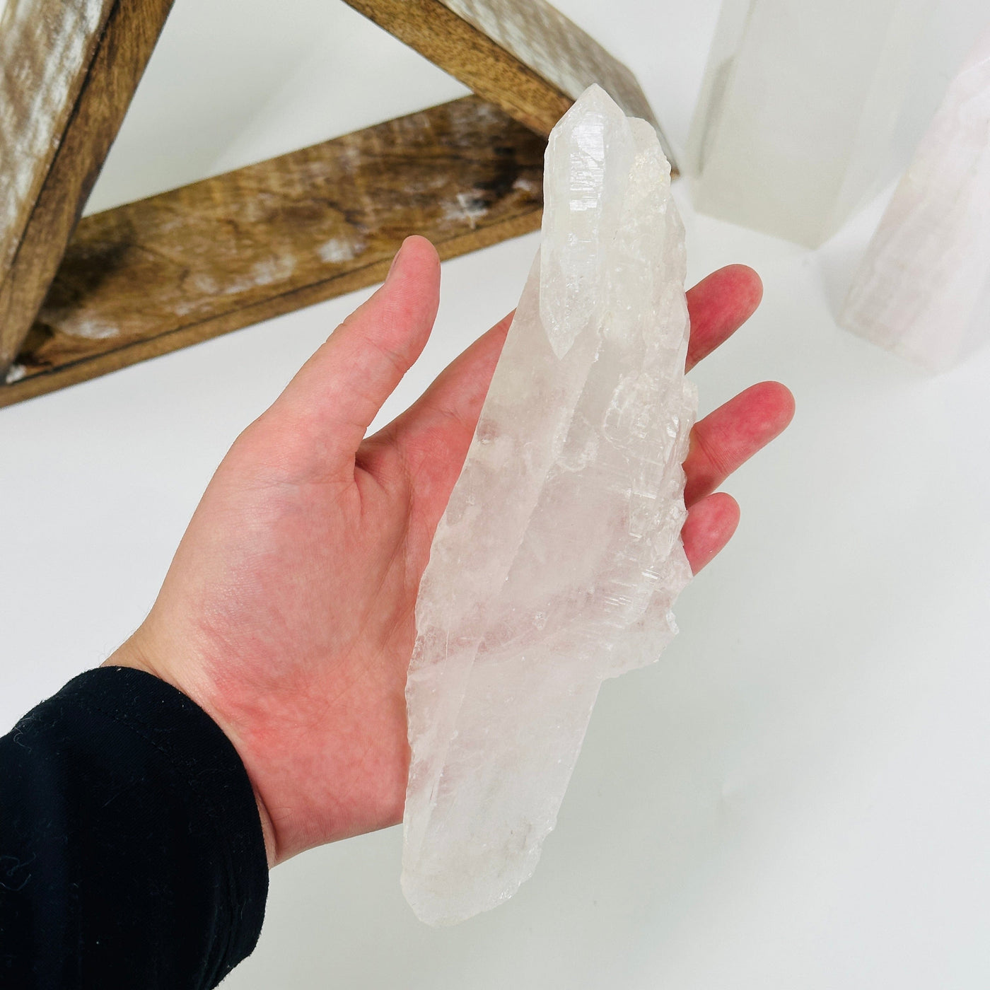 hand holding up crystal quartz with decorations in the background
