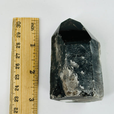 smokey quartz polished point next to a ruler for size reference