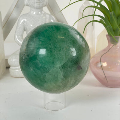 Fluorite Crystal Sphere on a stand  for display with other items in the background