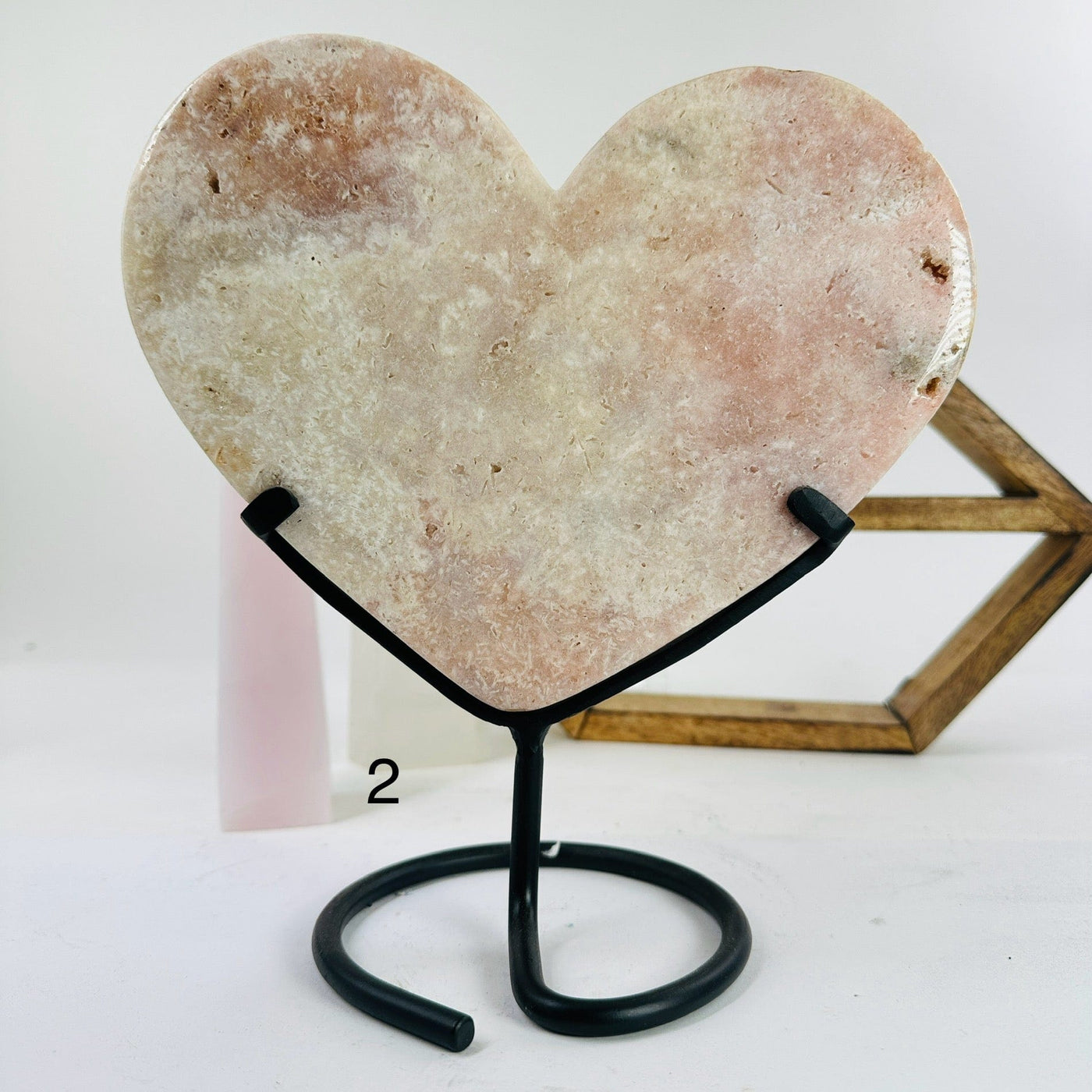 pink amethyst heart on metal stand with decorations in the background