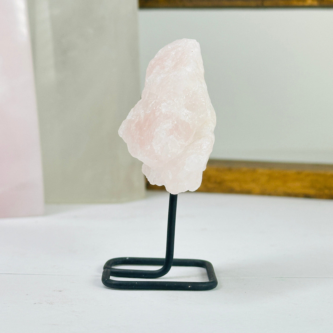 Rose quartz on metal stand with decorations in the background