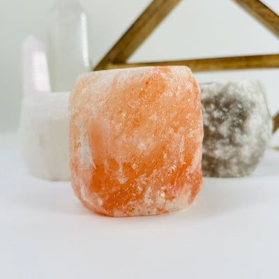 HIMALAYAN SALT CANDLE HOLDER WITH DECORATIONS IN THE BACKGROUND