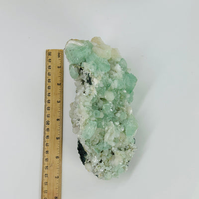 green apophyllite next to a ruler for size reference