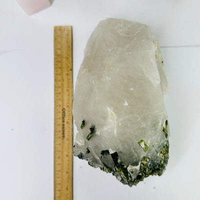 green tourmaline on matrix next to a ruler for size reference