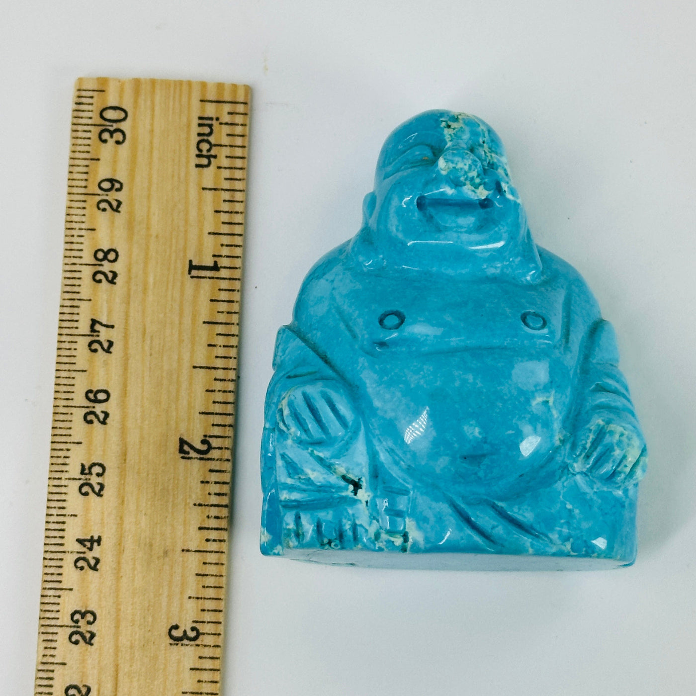 blue howlite buddha statue next to a ruler for size reference