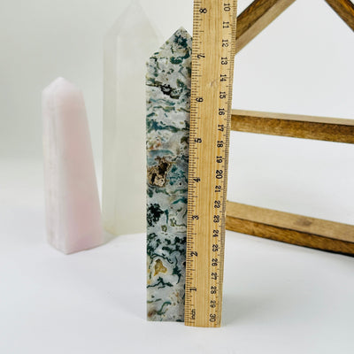 moss agate polished point next to a ruler for size reference