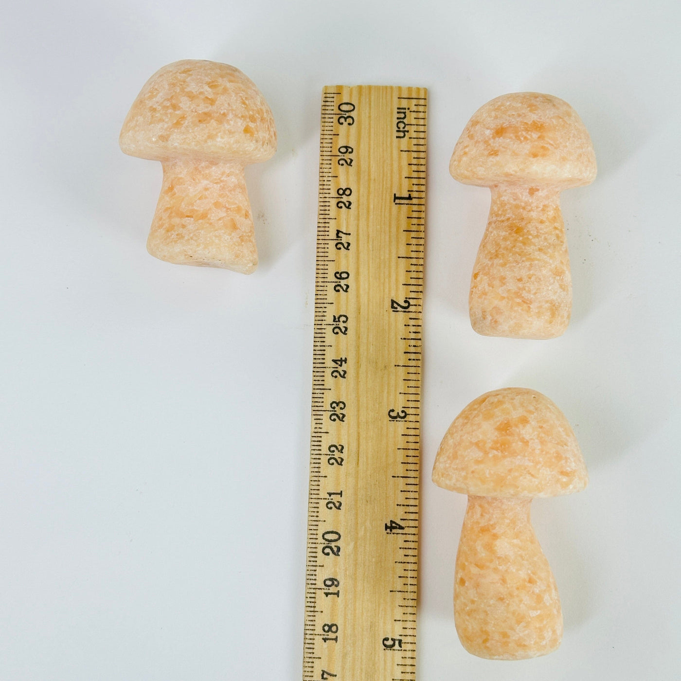 peach calcite mushroom next to a ruler for size reference