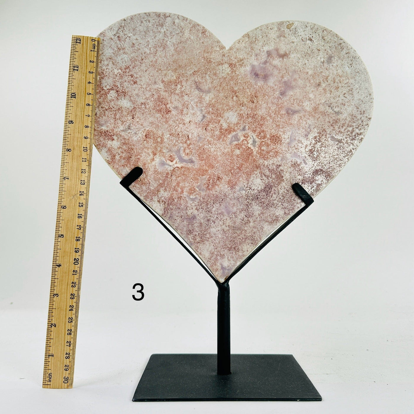 pink amethyst heart on metal stand next to a ruler for size reference