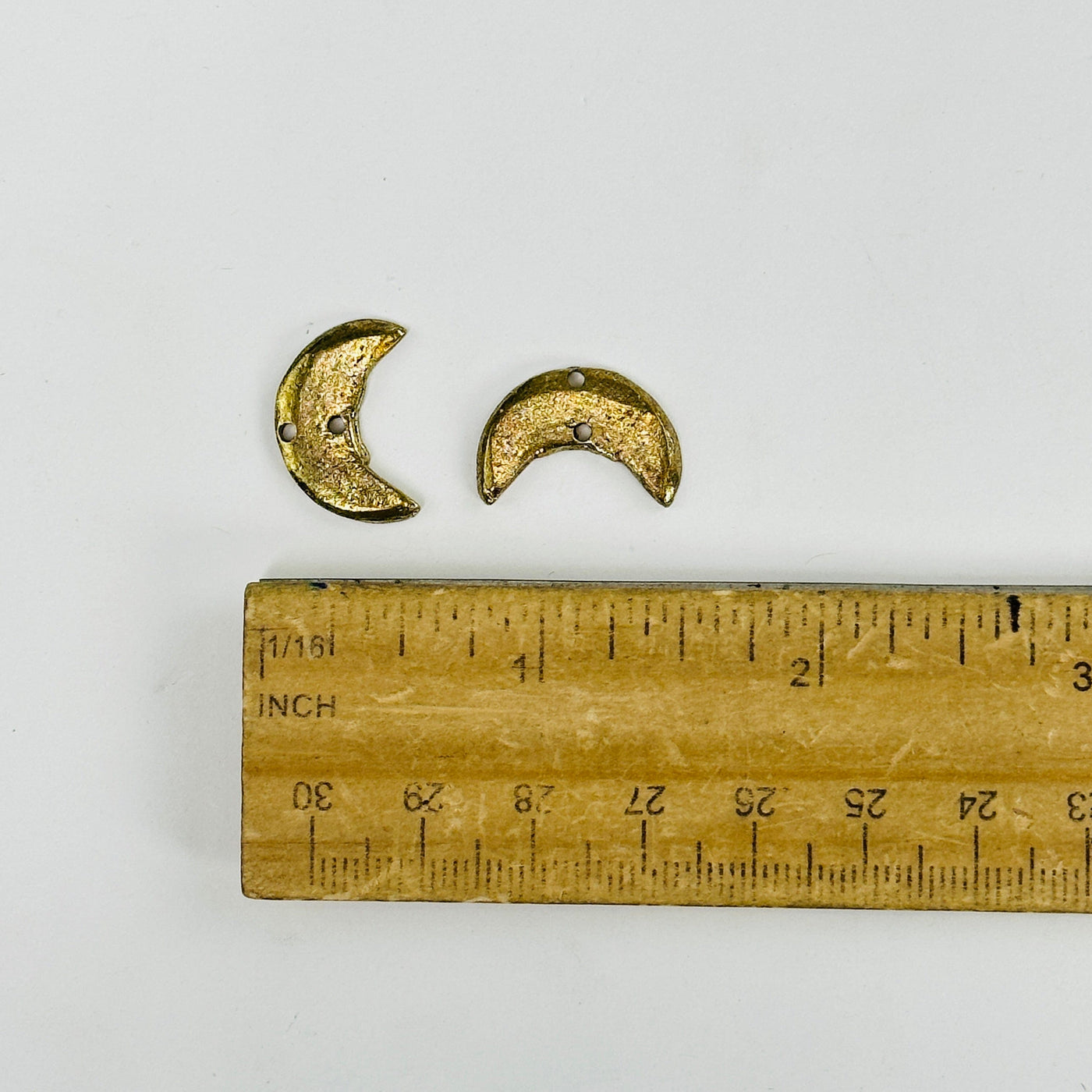 moon pendants next to a ruler for size reference
