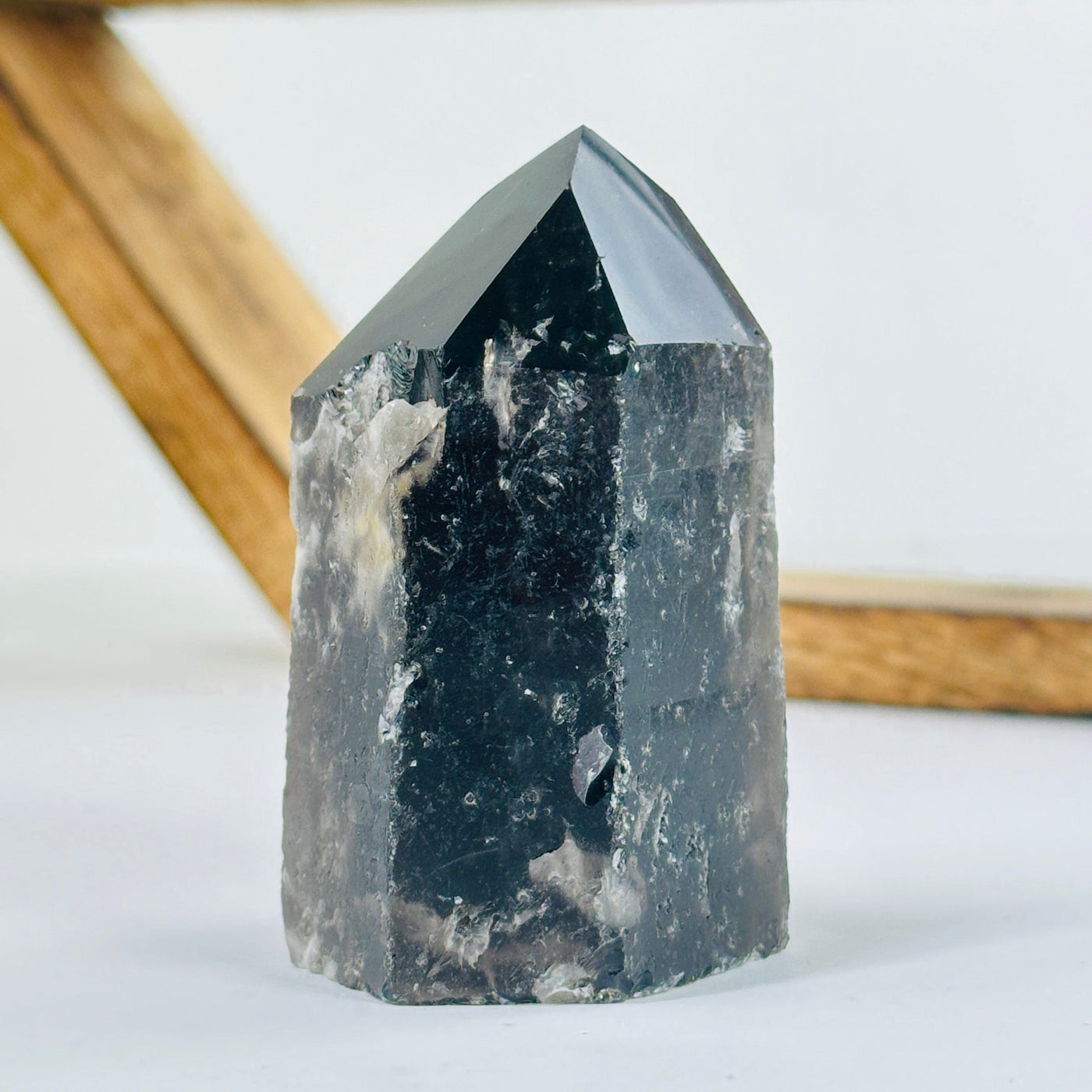 smokey quartz polished point with decorations in the background