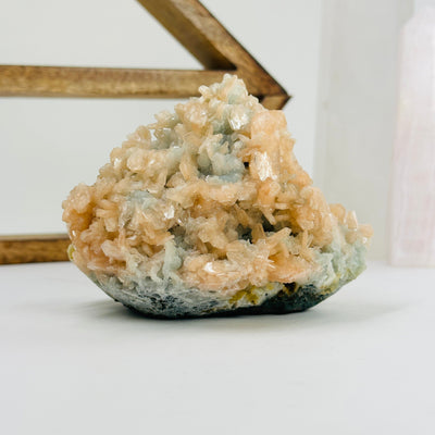 green apophyllite with peach stilbite with decorations in the background
