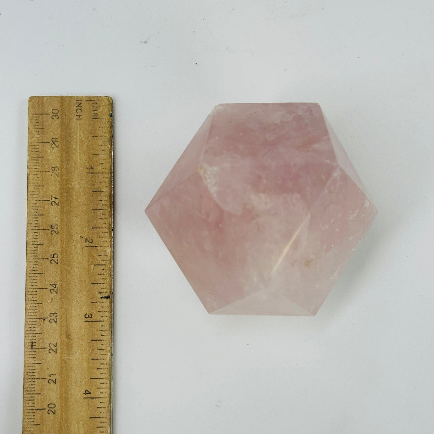 rose quartz dodecahedron next to a ruler for size reference