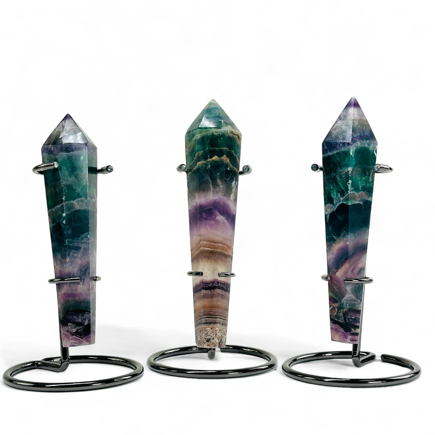 Three Rainbow Fluorite Crystal Wand Points on metal stands with a white background.