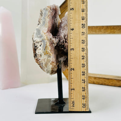 pink amethyst on metal stand next to a ruler for size reference