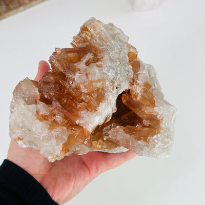 hand holding up tangerine quartz cluster