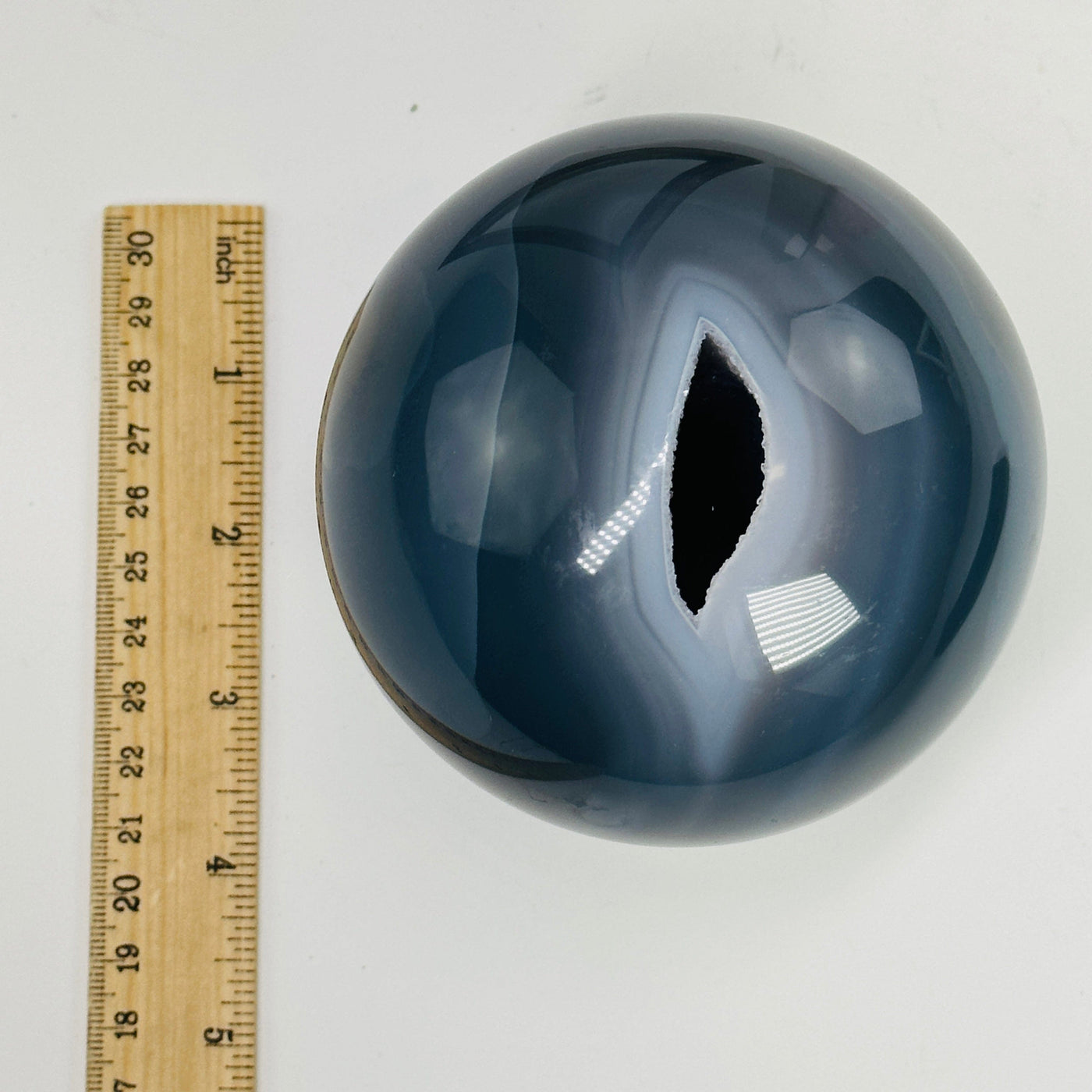 agate sphere next to a ruler for size reference