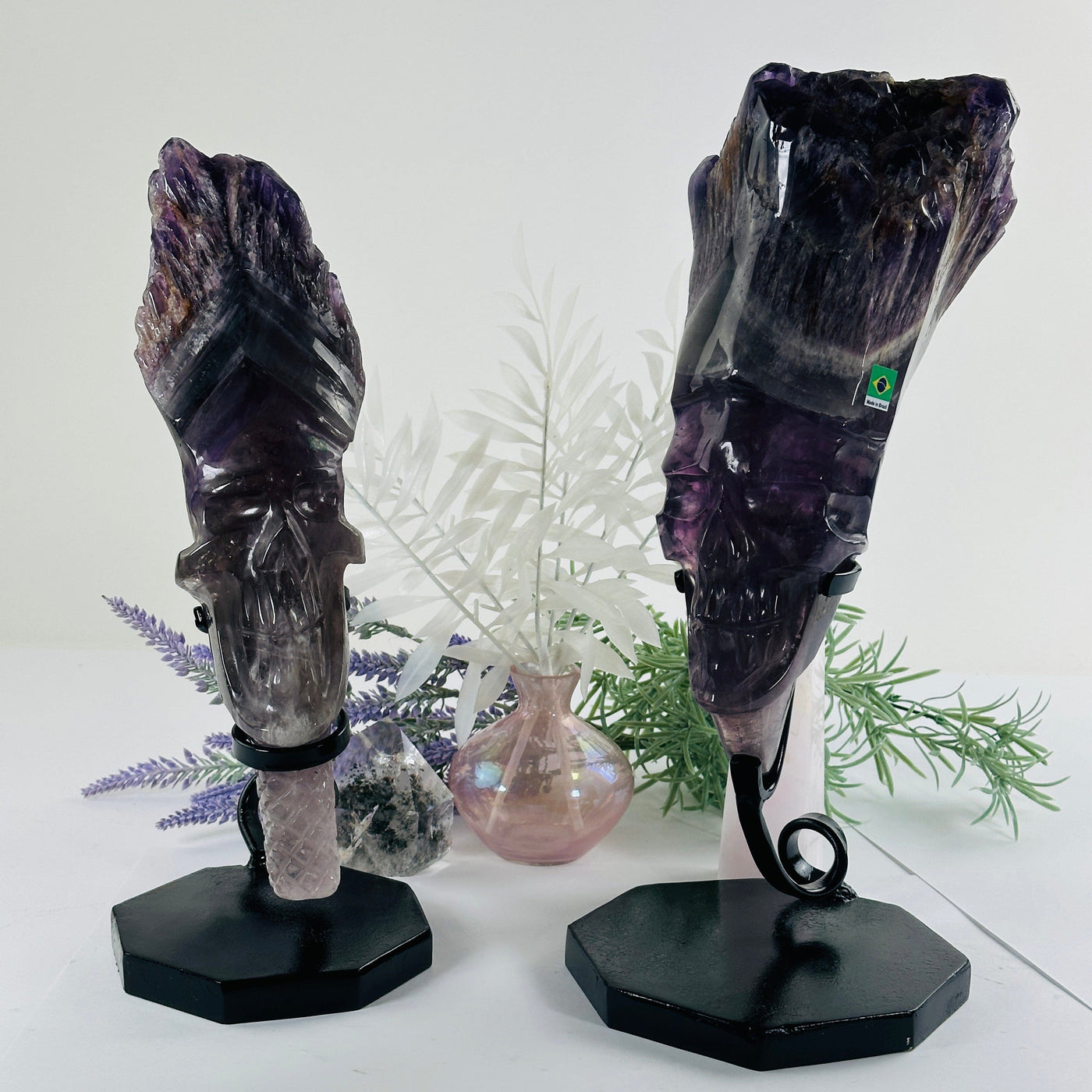 Elestial Amethyst Crystal Skull Sculpture on Stand - You Choose both variants front view with props and plants in the background