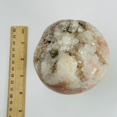 pink amethyst sphere next to  ruler for size reference