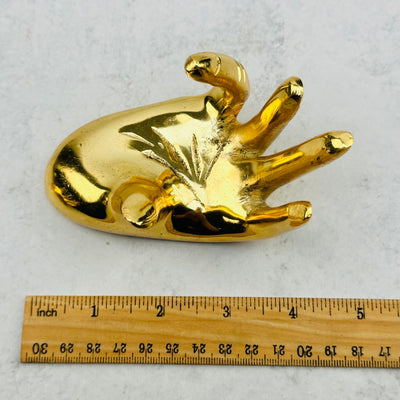 Gold Hand Holder next to a ruler for size reference 