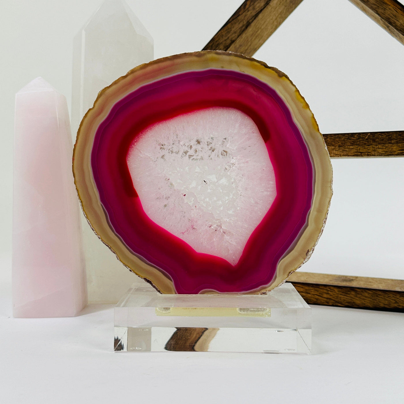 Pink agate slice on acrylic stand with decorations in the background