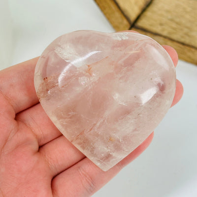 ROSE QUARTZ HEART WITH DECORATIONS IN THE BACKGROUND