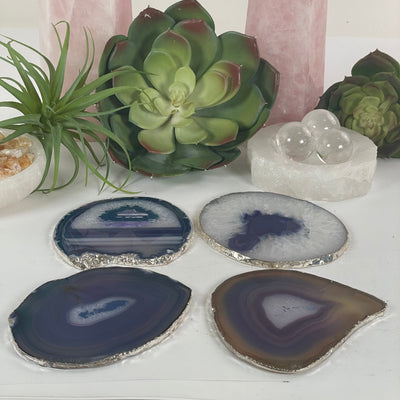 Teal and Purple Agate Slice Coasters Set with Silver Electroplated Edges - Set of 4 Coasters side view with props and plants in the background